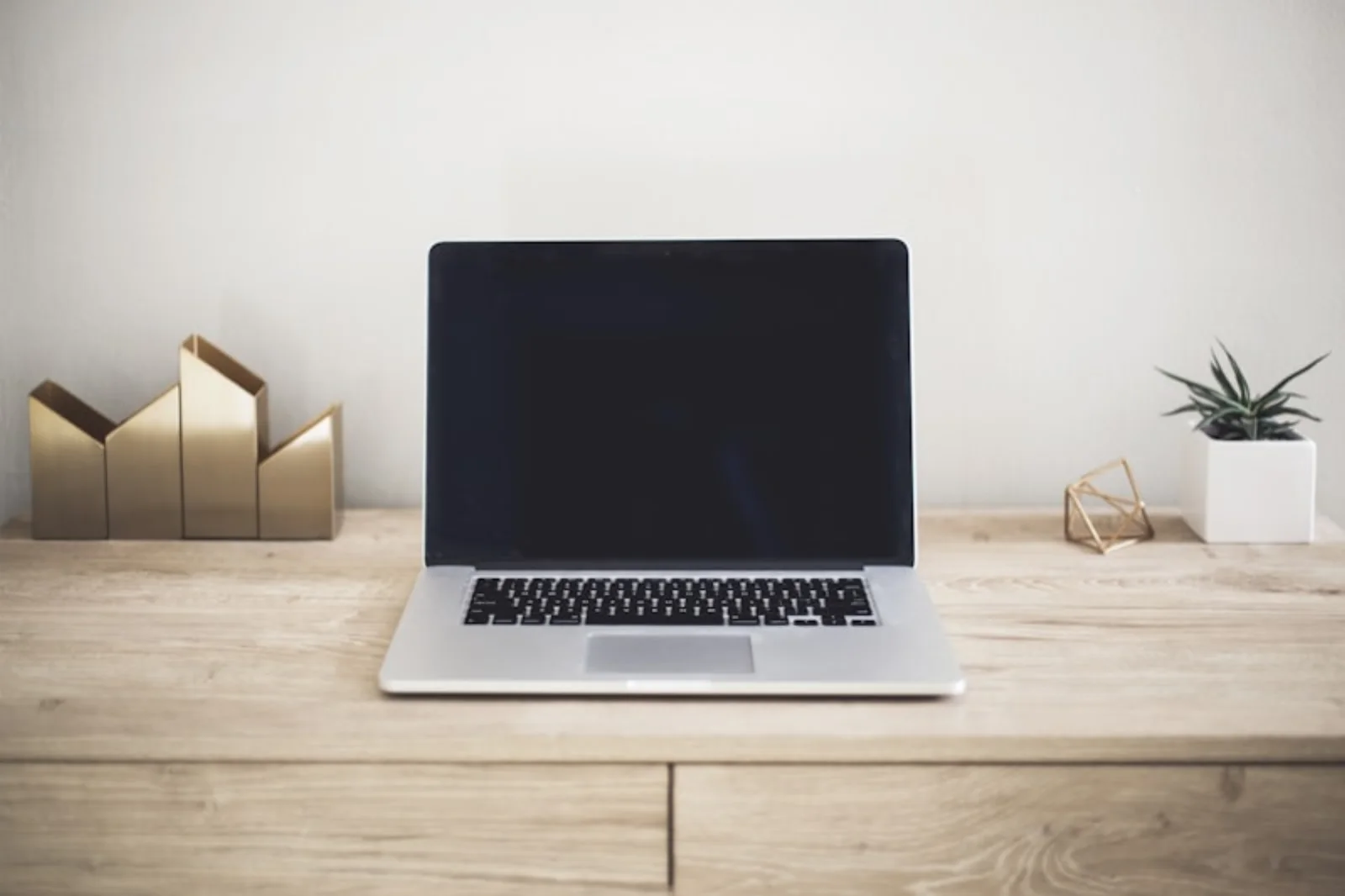 Laptop op een licht houten bureau, klaar om in gebruik te nemen